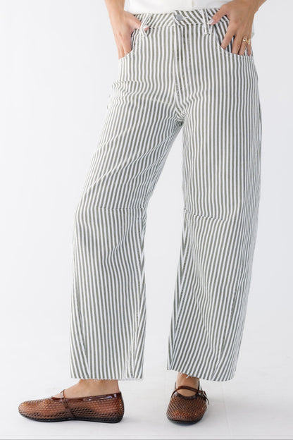 Young woman wearing  wide cut, barrel jeans in white and olive stripe with pockets.