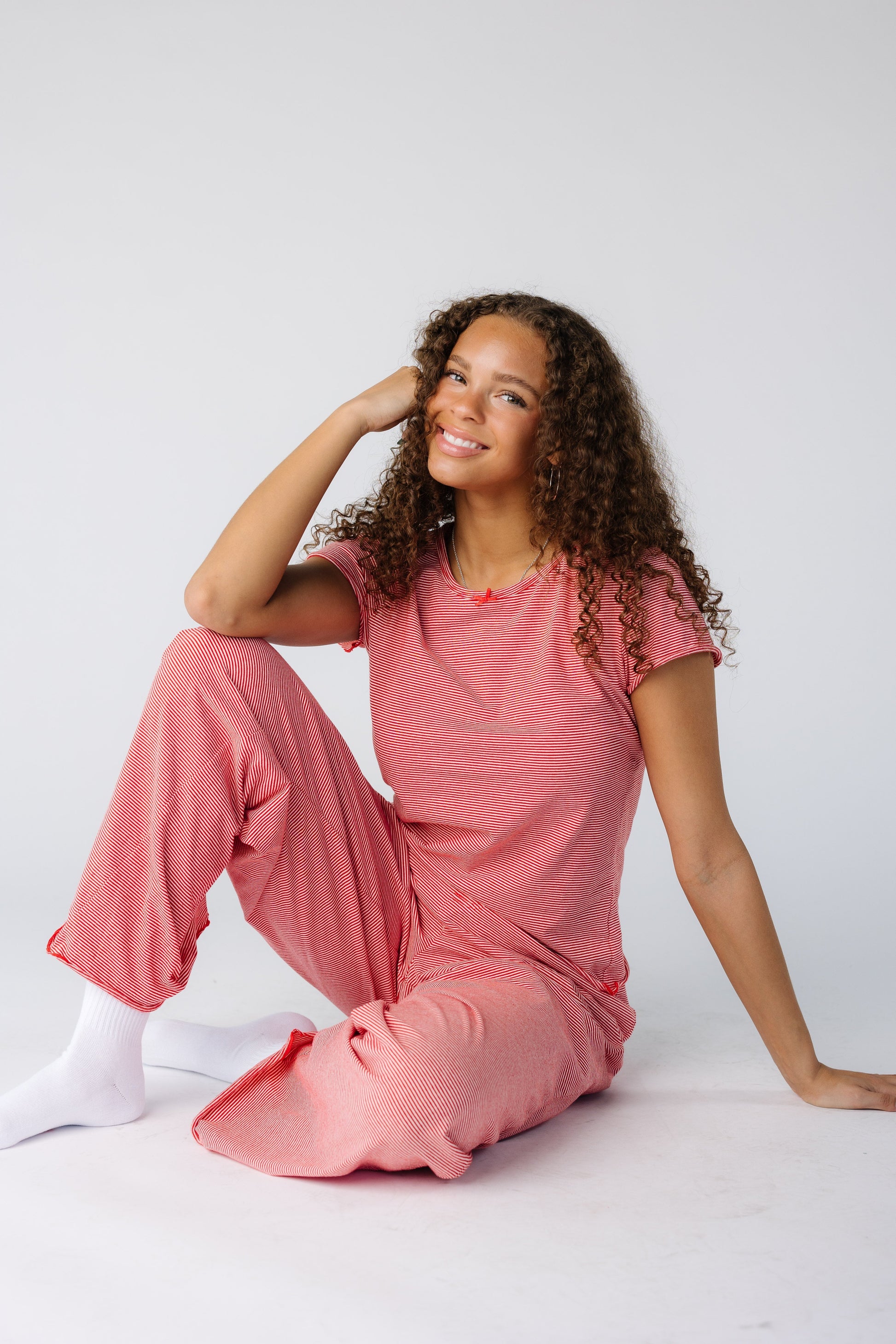 Woman sitting and wearing a red stripe pajama set