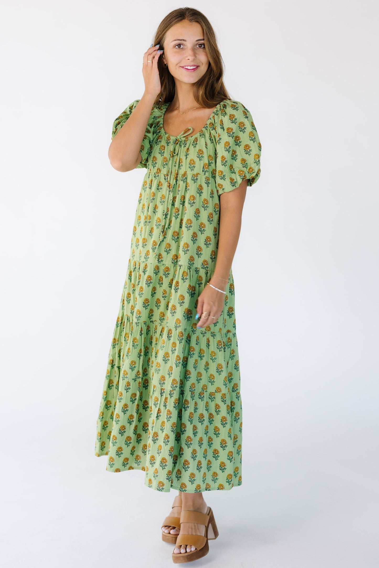 Full length view of a young woman wearing a green loose fitting dress with large balloon short sleeves.