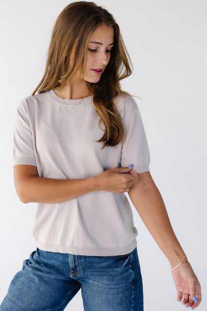 Woman wearing a modest lightweight sweater in ight grey with a crew neckline and short sleeves.