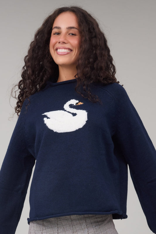 Young woman wearing a navy sweater with a large front swan graphic.