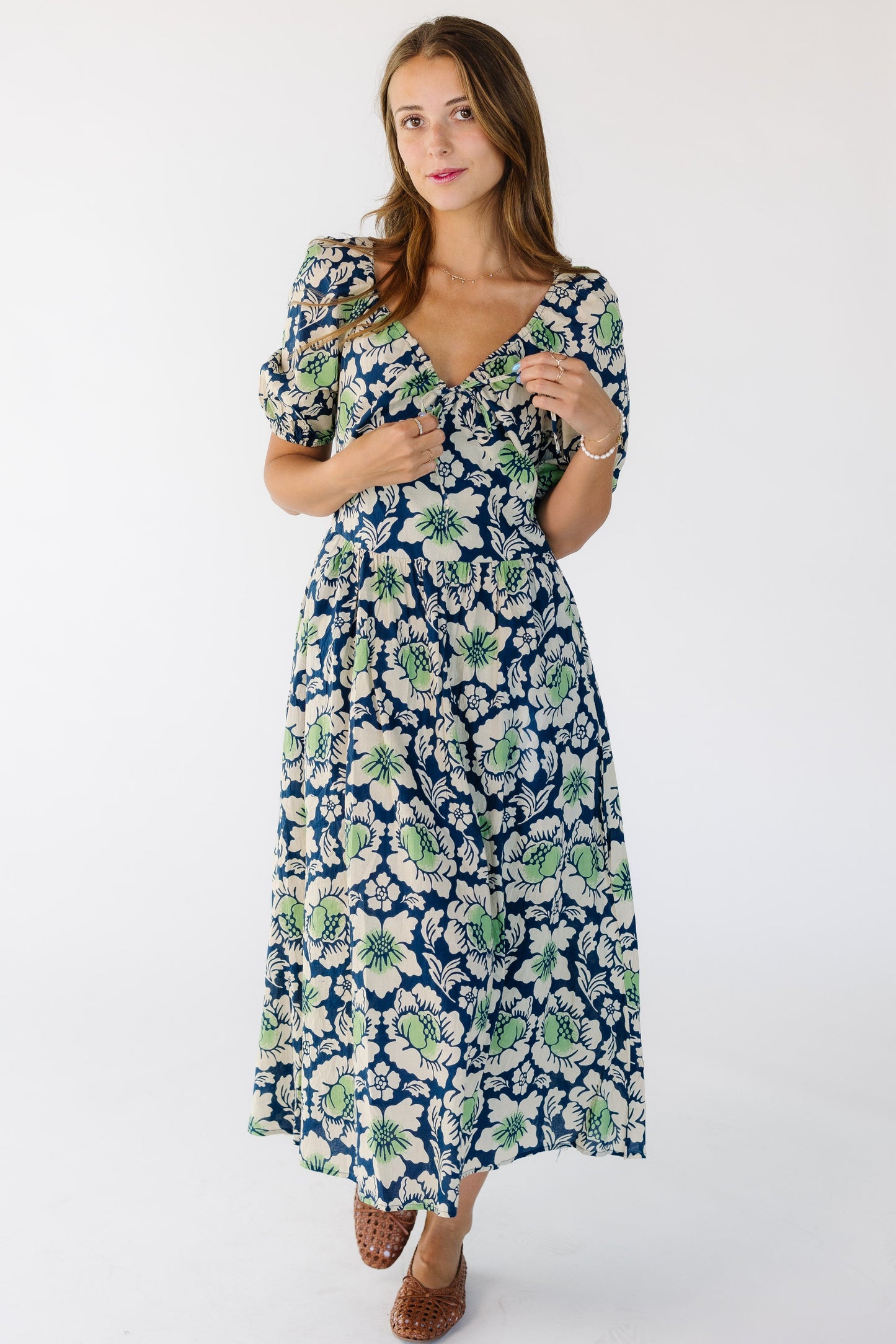 Woman wearing a blue and green bold floral dress with a full skirt and a close fitting waist and bodice.