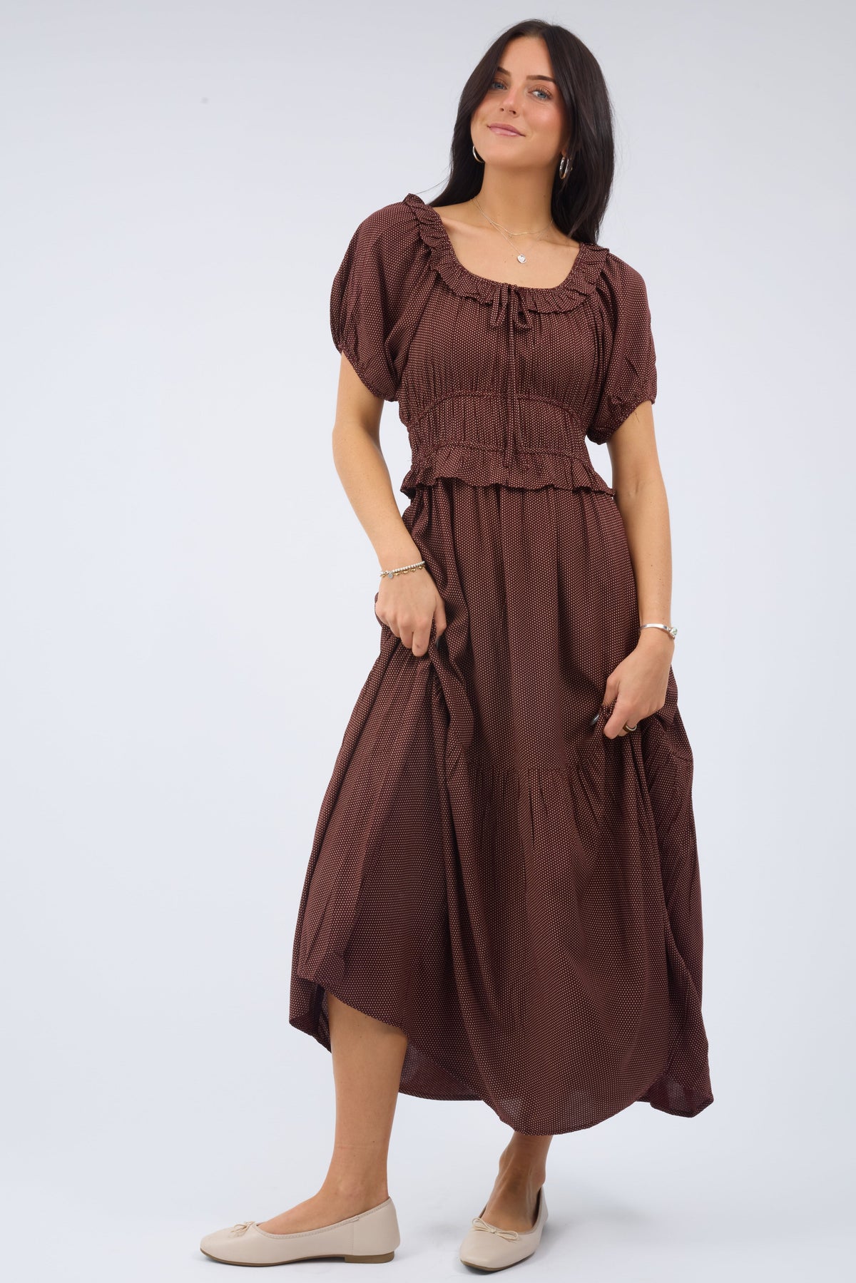 Young woman wearing a modest brown midi dress in a brown & tiny white polka dot dress with a scoop neckline and large puff sleeve and wide waist.