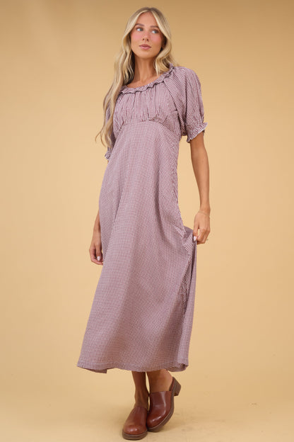 Woman wearing a brown gingham midi dress with a gathered bodice scoop & ruffled neckline and puff sleeves.