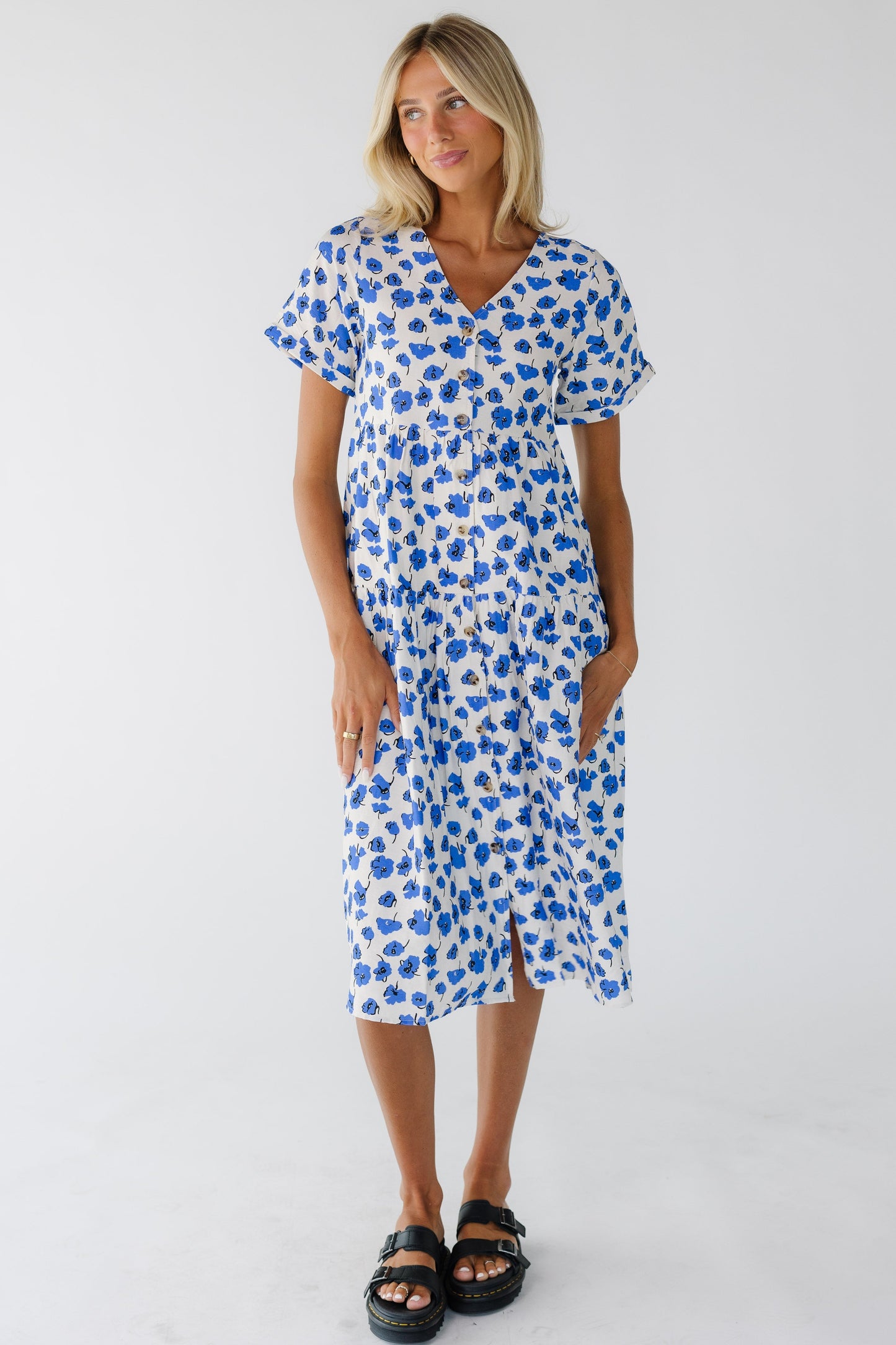 Young woman wearing a white and blue floral print button down midi dress with a V-neckline and short sleeves.