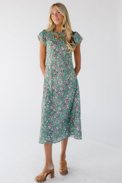 Young woman wearing a modest green floral midi dress with a round neckline and puffy cap sleeves.