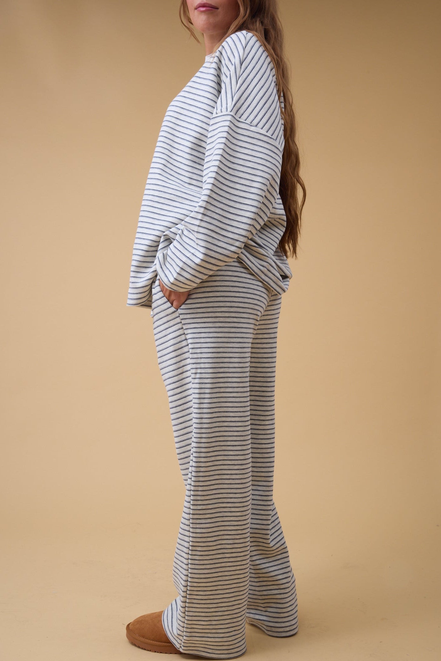 Back view of a woman wearing a grey stripe lounge set with side pockets.