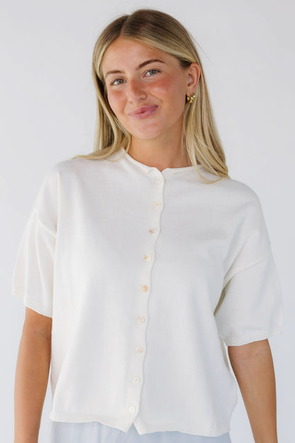 Young woman wearing a modest ivory button down cardigan with a rolled round neckline and short sleevs.