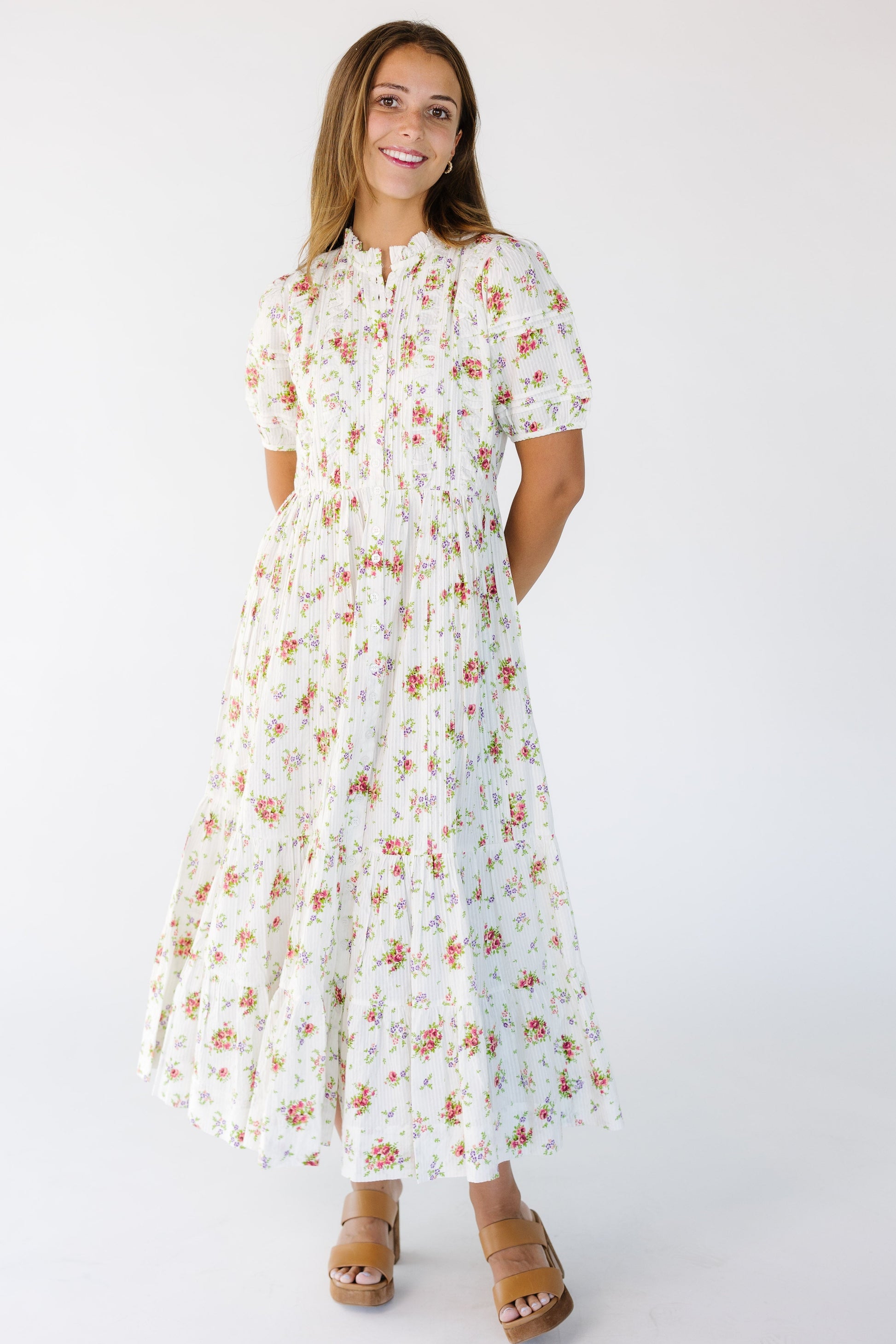 Young woman wearing a modest cream floral print buttondown midi dress with short puff sleeves and ruching and pleat details.