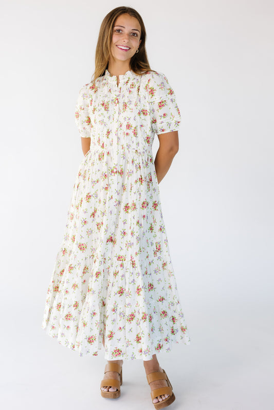 Young woman wearing a modest cream floral print buttondown midi dress with short puff sleeves and ruching and pleat details.