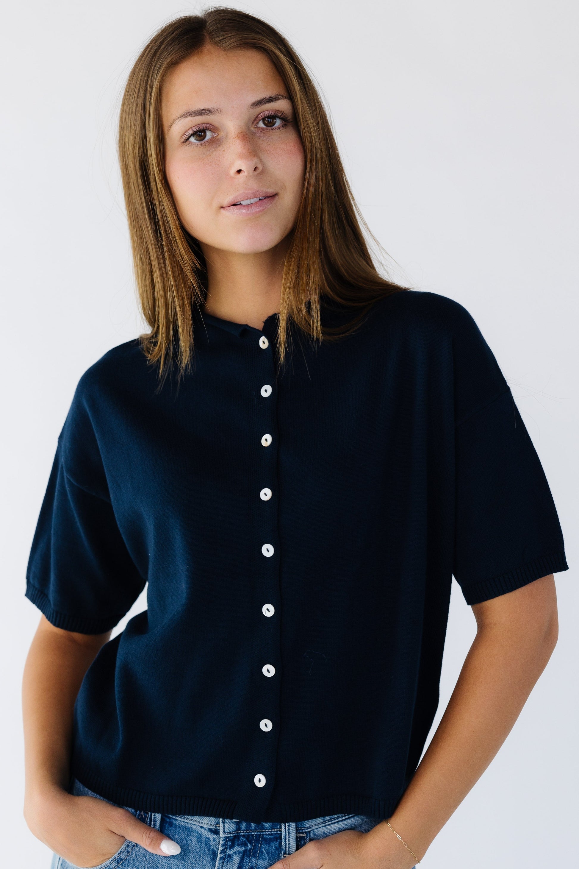 Woman wearing a button down navy cardigan with short sleeves.