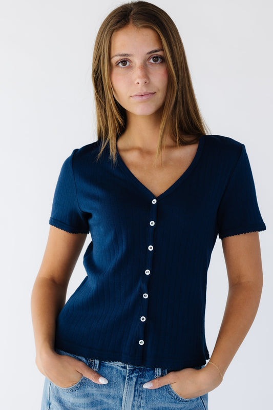 Young woman wearing a modest navy soft pointelle V-neck top with short sleeves.