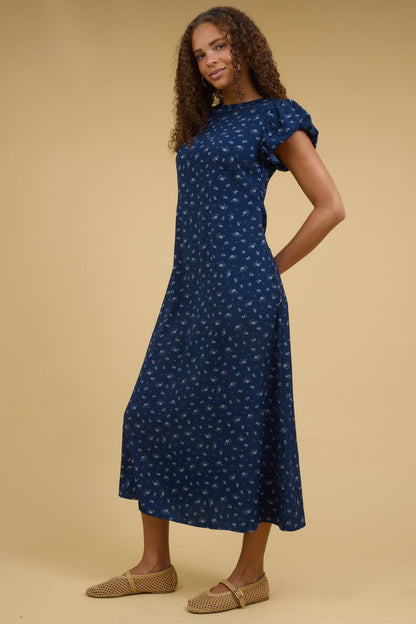 Teenage girl wearing a modest blue floral midi dress with short gathered cap sleeves.