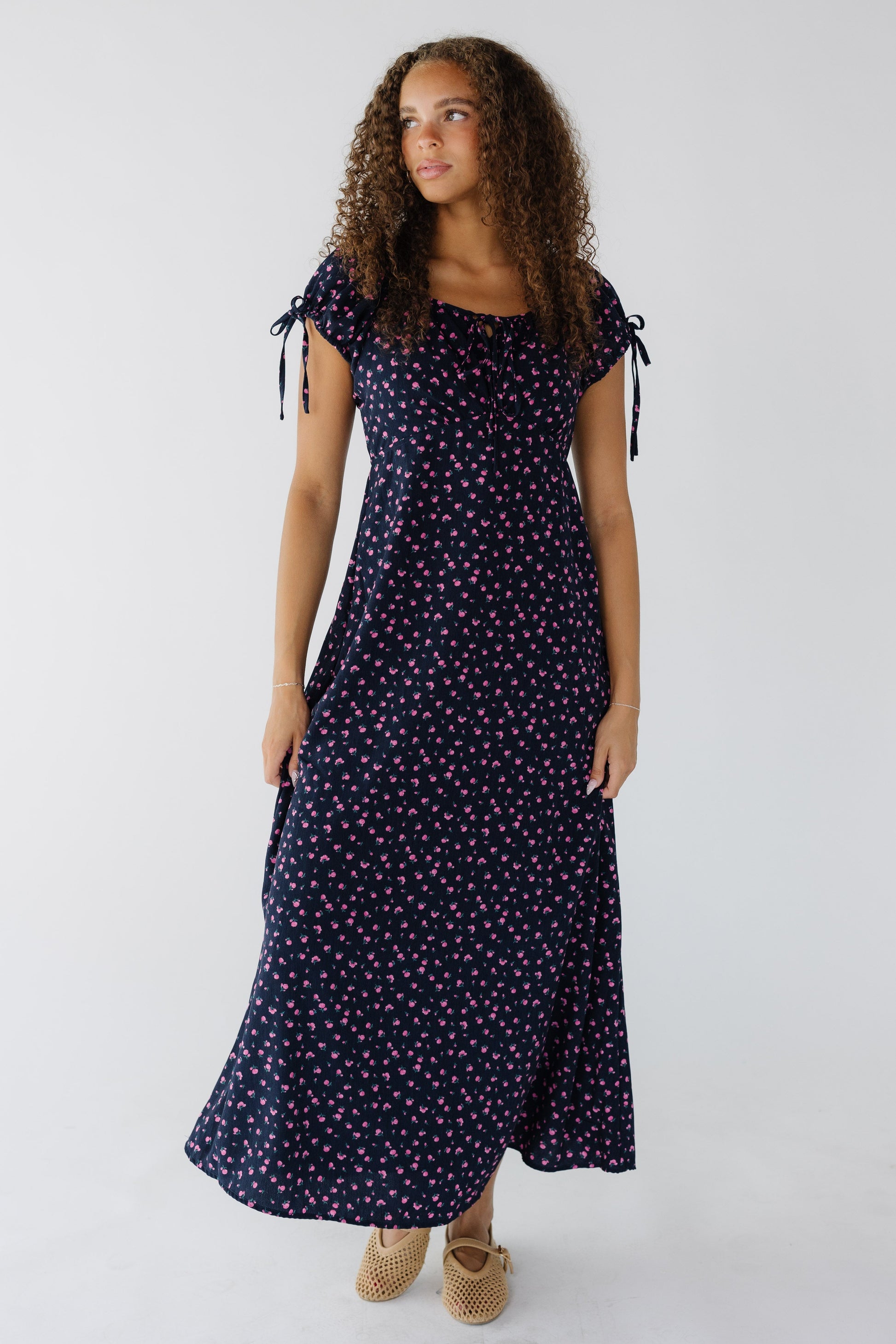 Teenage girl wearing a navy & pink floral midi-maxi dress with and empire waist and short puff sleeves.