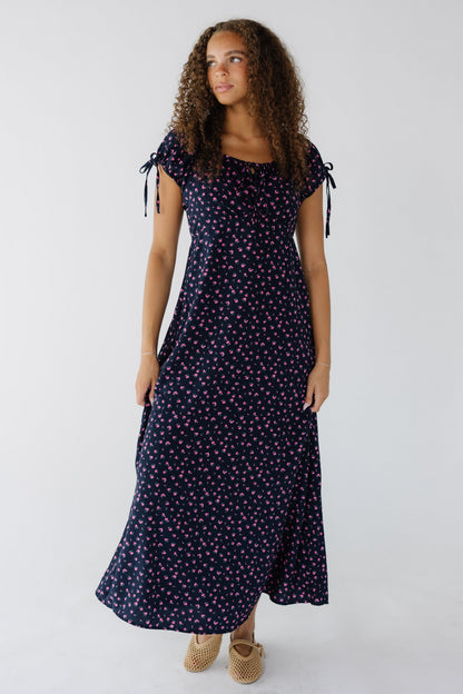 Teenage girl wearing a navy & pink floral midi-maxi dress with and empire waist and short puff sleeves.