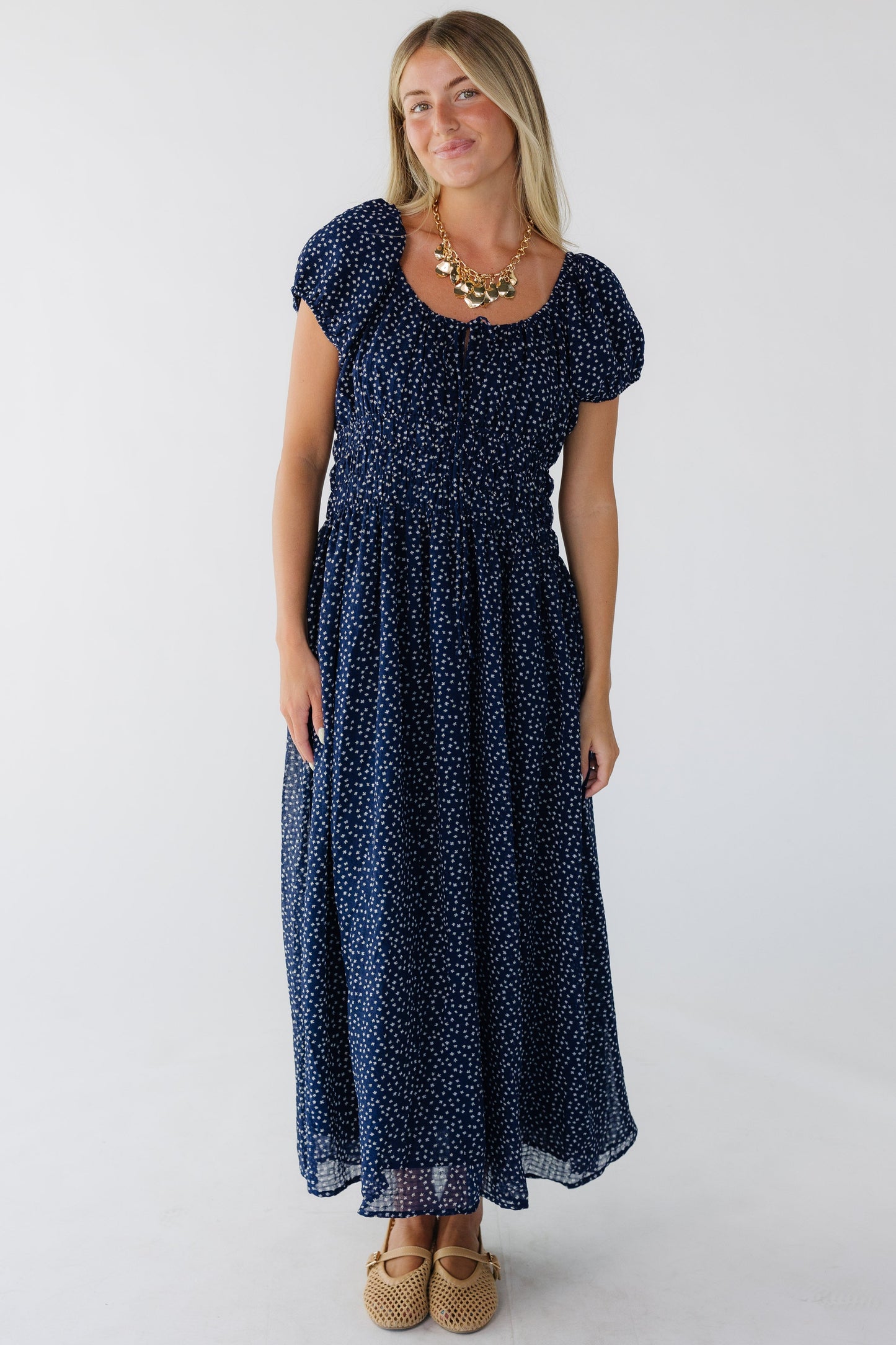 Young woman wearing a navy print midi dress with a scoop neckline, puff sleeves and a wide elastic waist.