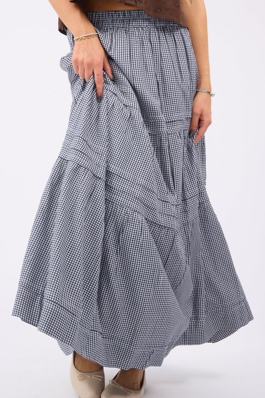 Young woman wearing a modest navy gingham maxi skirt with pleats and tiers.
