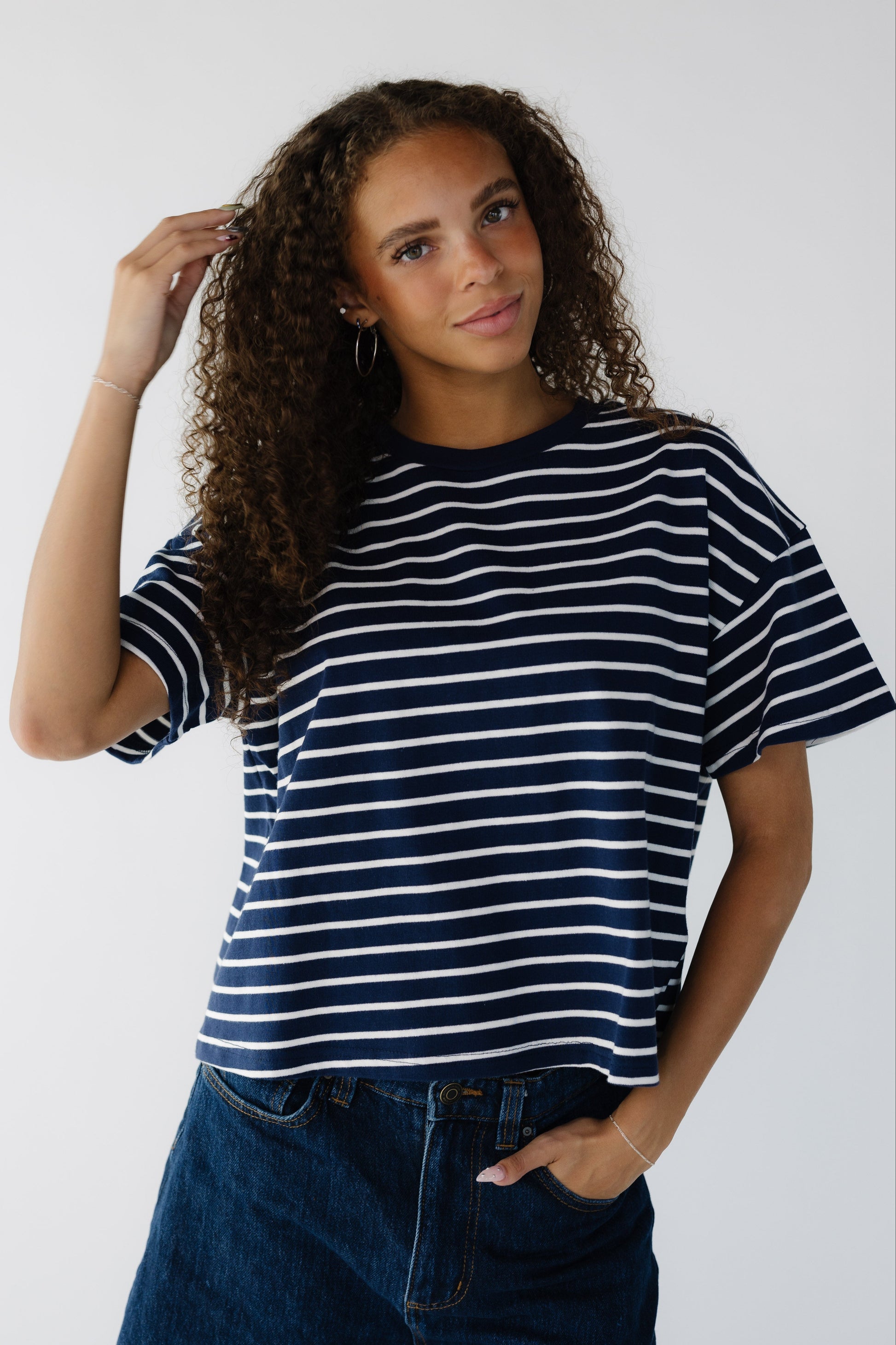 Teen age girl wearing a modest navy & white stripe loose fitting tee with short sleeves.