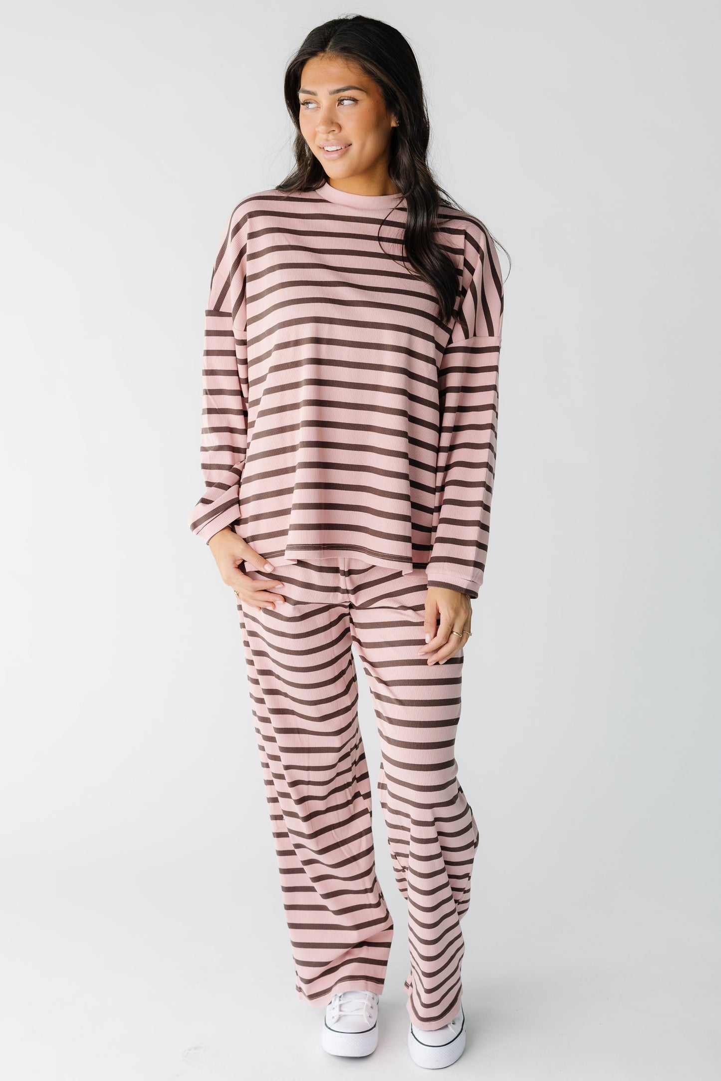 Woman wearing a loose fitting pink and brown loose fitting lounge set with long sleeves and long wide leg pants.