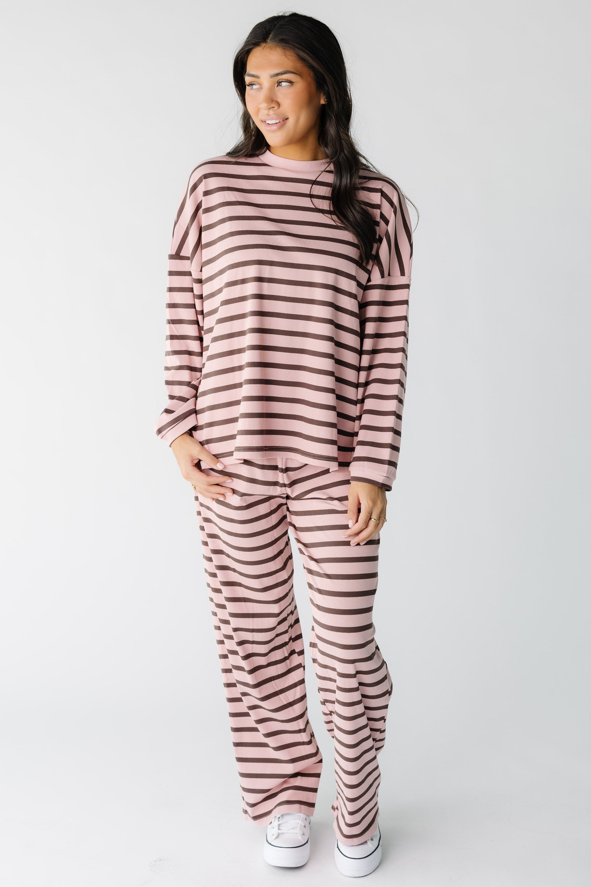 Woman wearing a loose fitting pink and brown loose fitting lounge set with long sleeves and long wide leg pants.