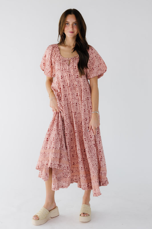 Young woman wearing a modest pink print midi maxi dress witha kercheif hem, lce insets near the hem, empire waist, balloon sleeves and a drawstring scoop neckline.