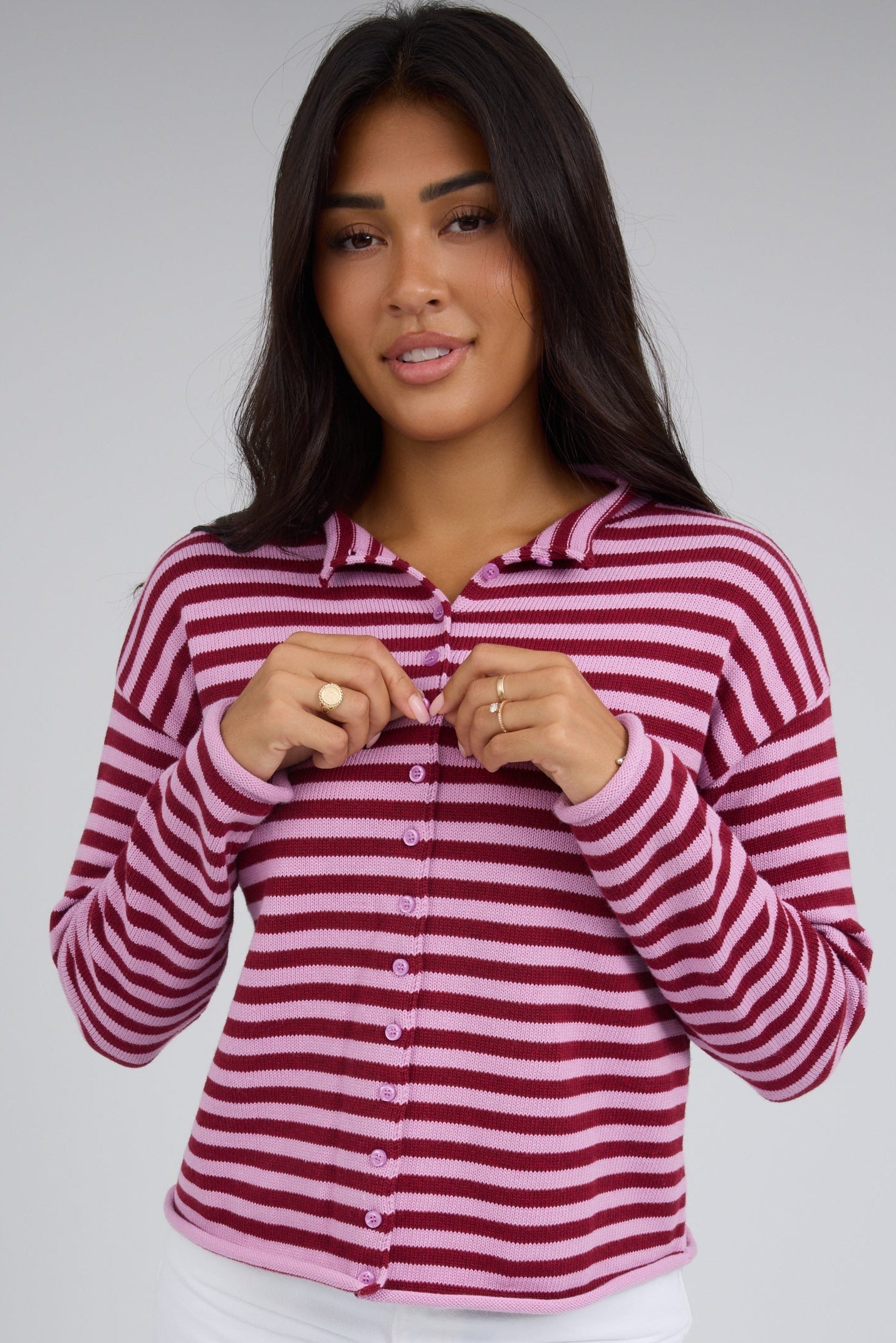 Young woman wearing a modest pink & red button down cardigan with long sleeves.