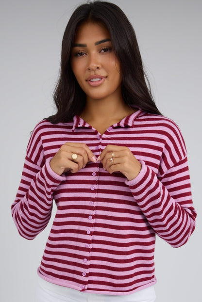 Young woman wearing a modest pink & red button down cardigan with long sleeves.