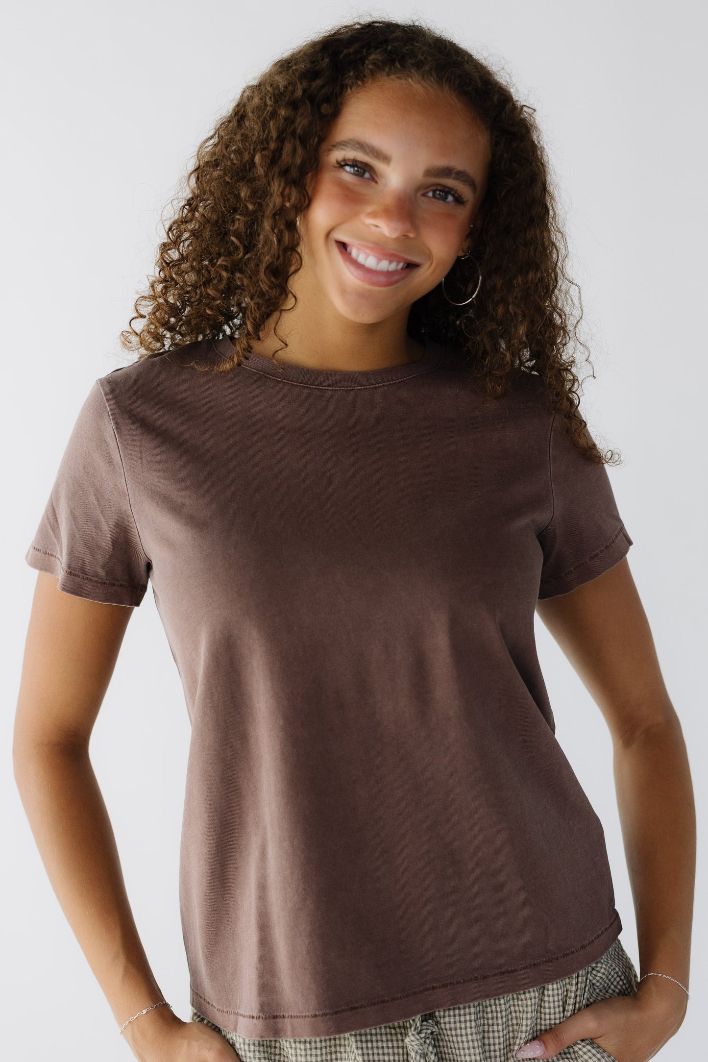 Teenage girl wearing a brown short sleeve tee with a round neckline.