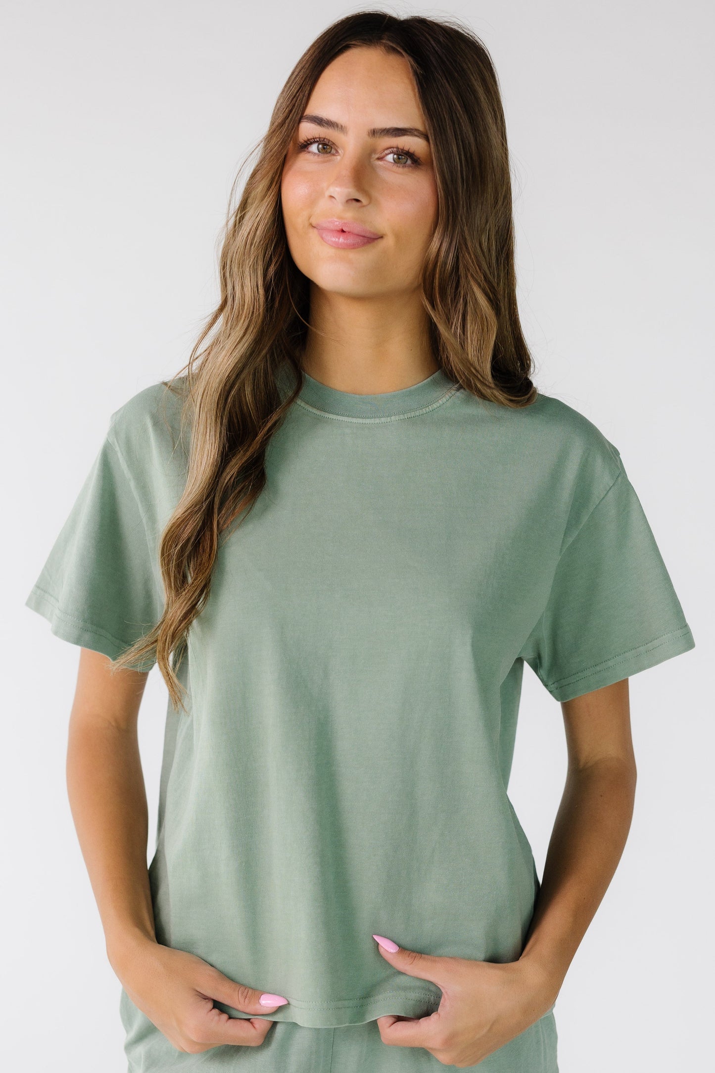 Young woman wearing a boxy cut short sleeve tee with a crew neckline.