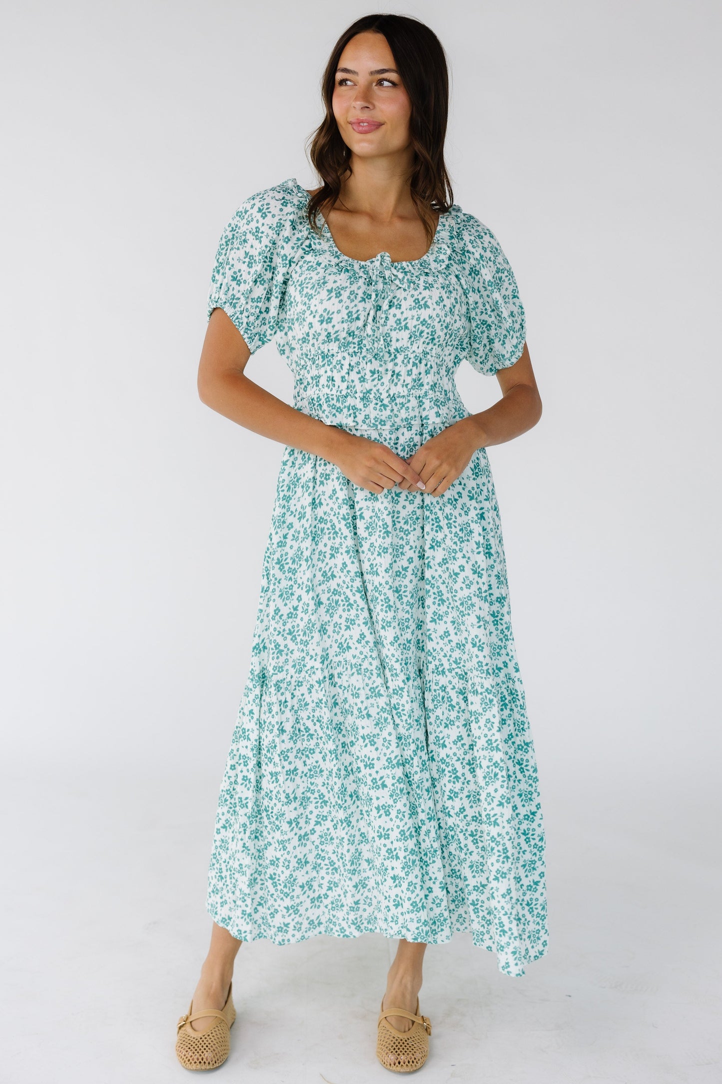 Young woman wearing a white with teal floral print midi dress with a scoop neckline , a full skirt and short puff sleeves.