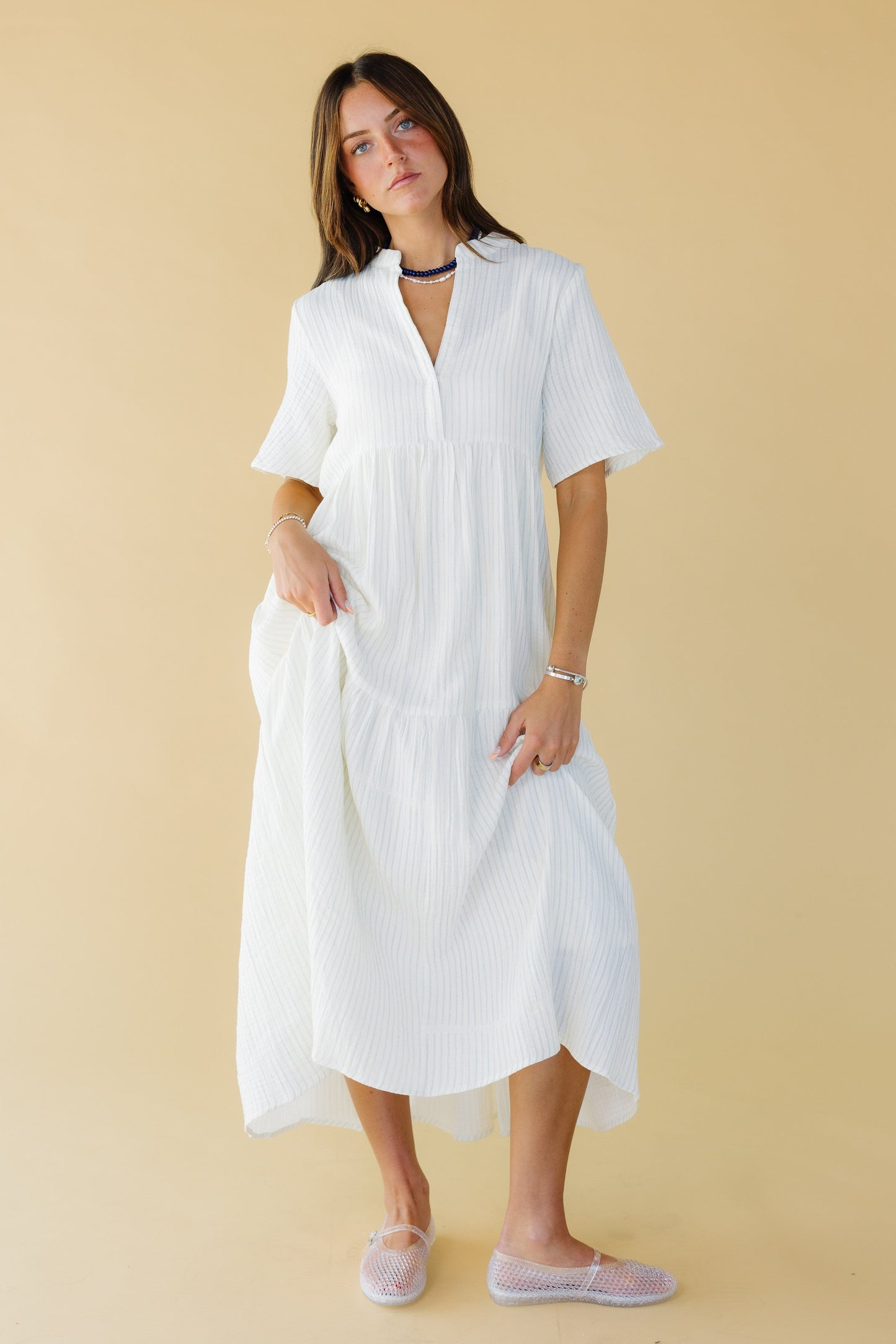 Young woman wearing a modest white stripe midi-maxi dress with short sleeves and a V-neckline.