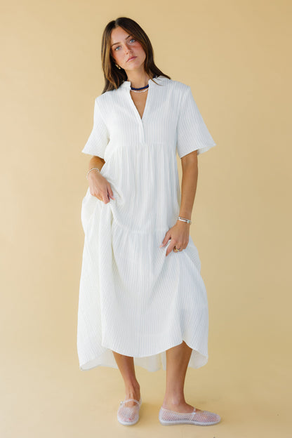 Young woman wearing a modest white stripe midi-maxi dress with short sleeves and a V-neckline.