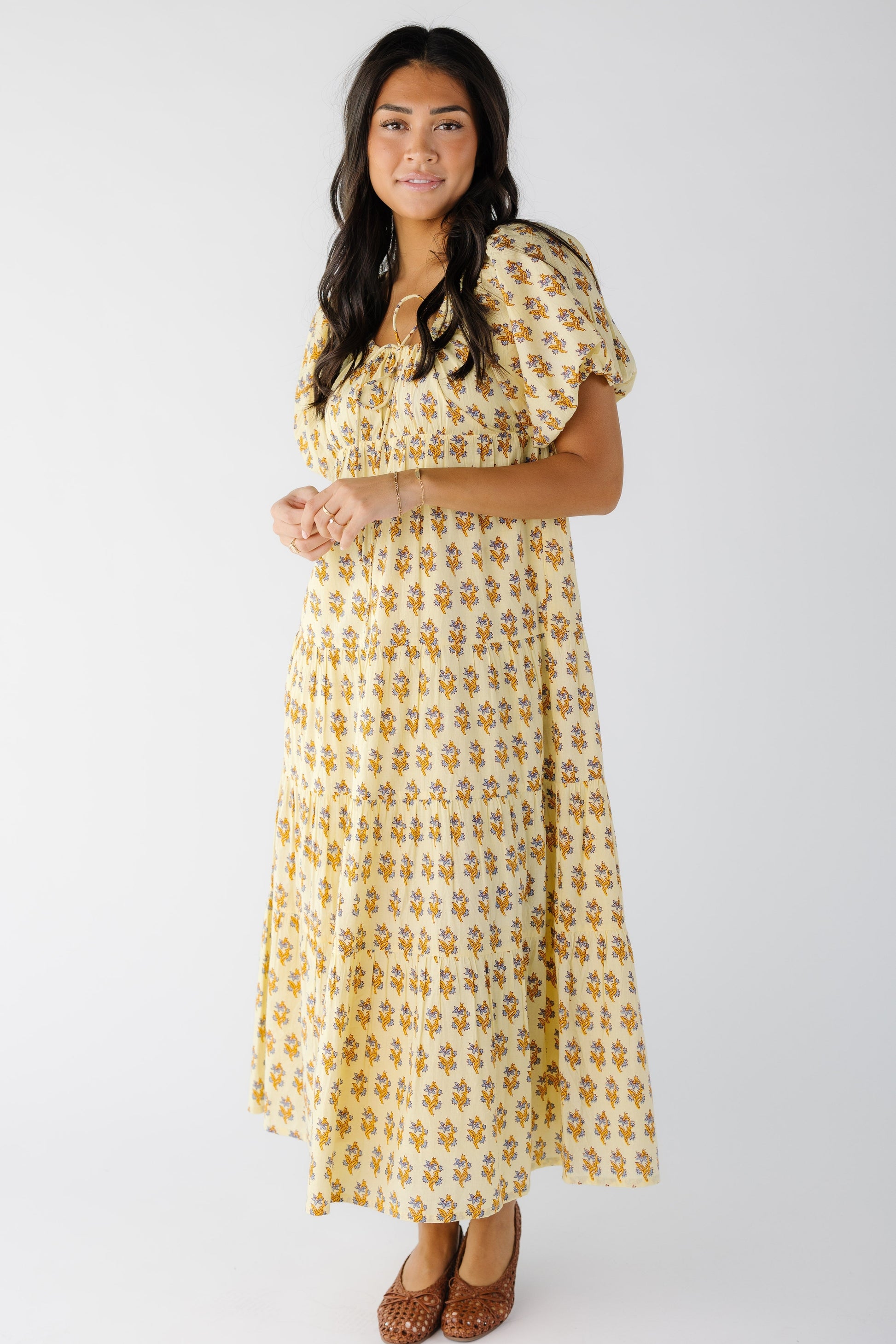 Woman wearing a modest yellow floral print midi-maxi dress with large balloon sleeves and gathered close fitting bodice.