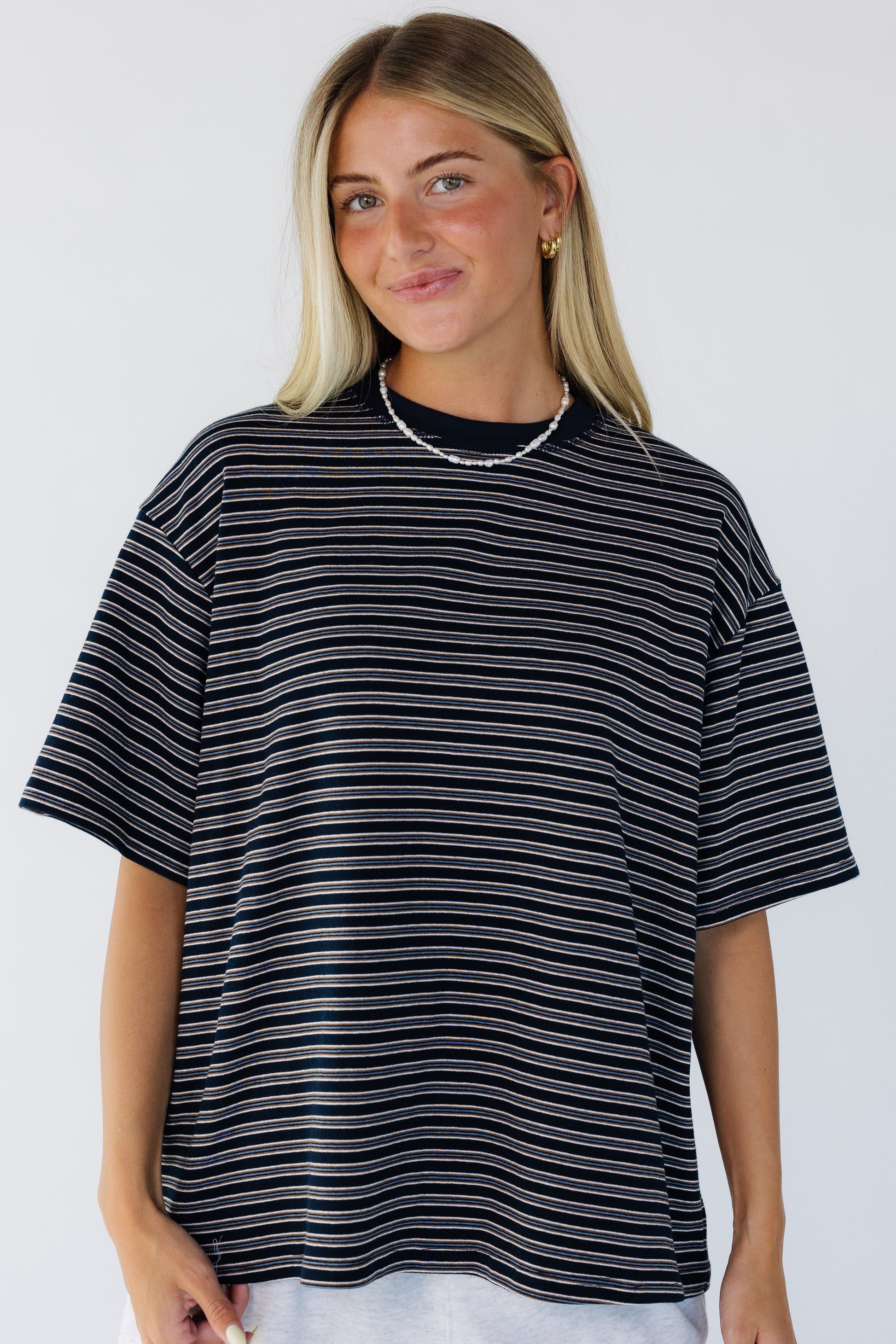Young woman wearing a loose fitting stripe tee with short sleeves and a crew neckline.