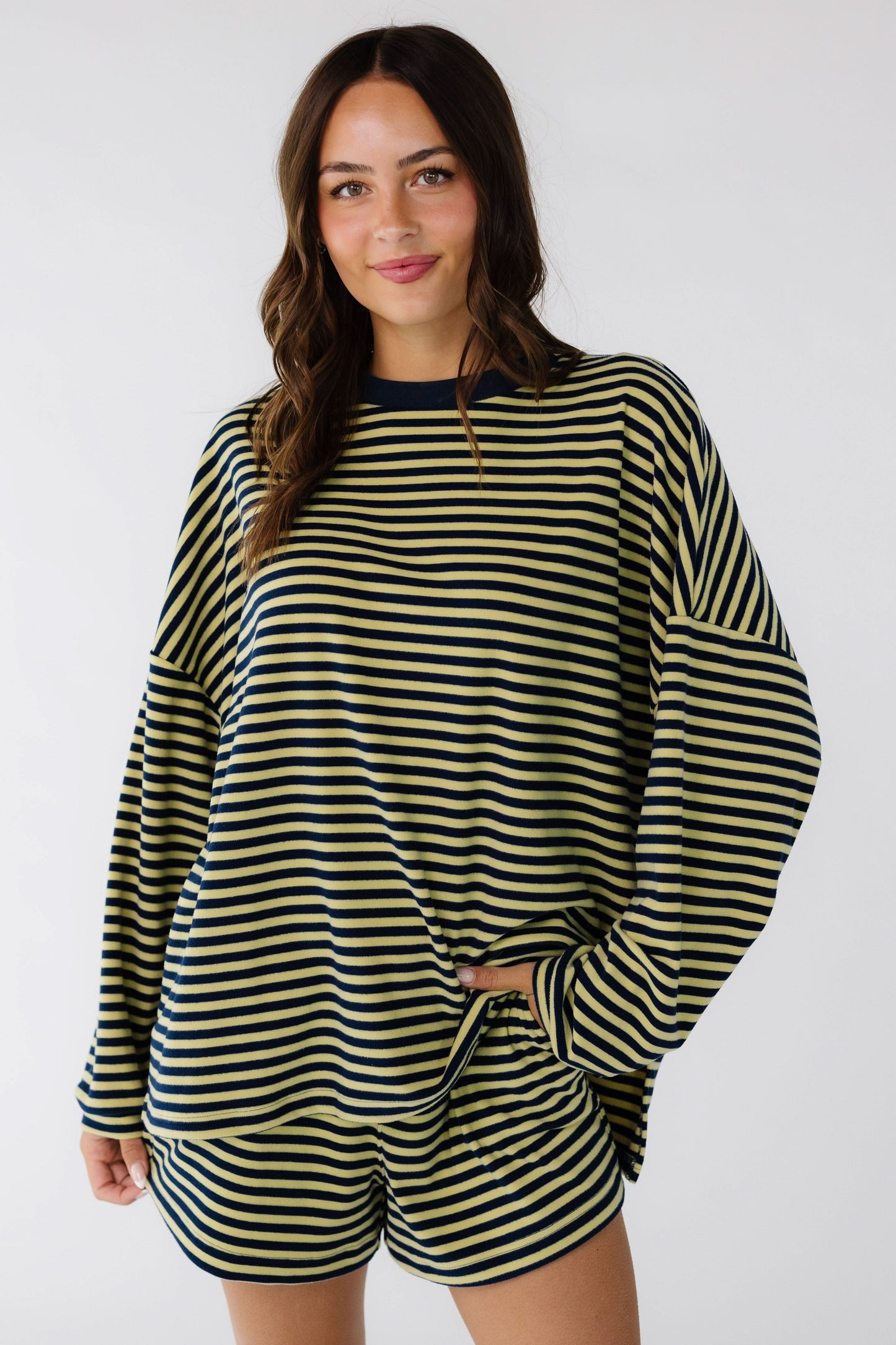 Woman wearing a yellow and navy stripe shorts set with drop shoulders, long sleeves and elastic waist shorts.