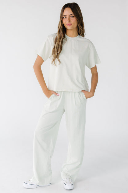 Woman wearing wide leg pants with a wide elastic waistband and side pockets.