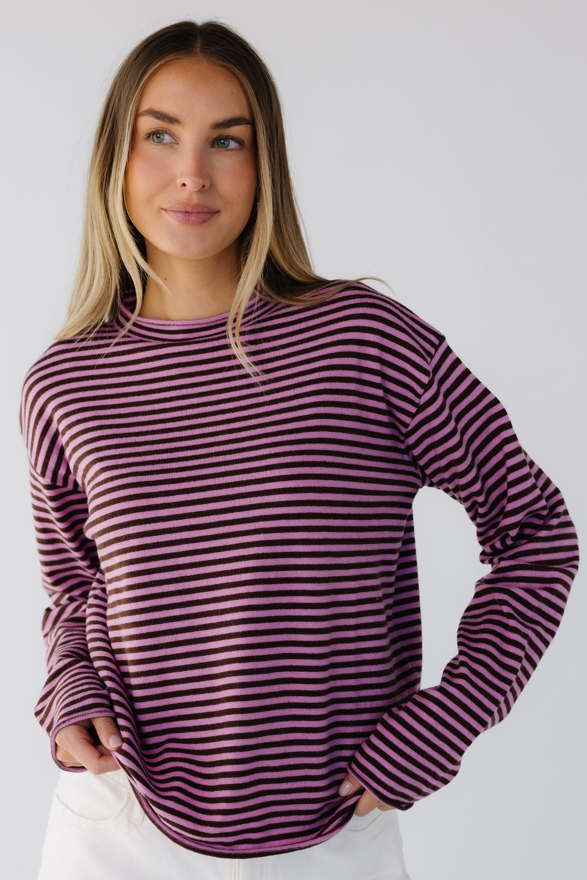 Woman wearing a pink & brown stripe lightweight knit sweater top with long sleeves and a mock turtleneck neckline.