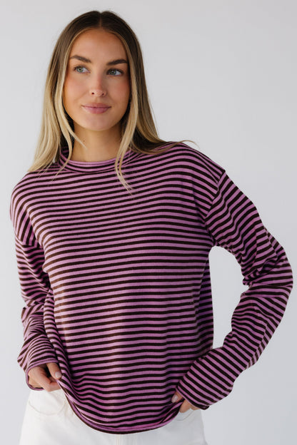 Woman wearing a pink & brown stripe lightweight knit sweater top with long sleeves and a mock turtleneck neckline.