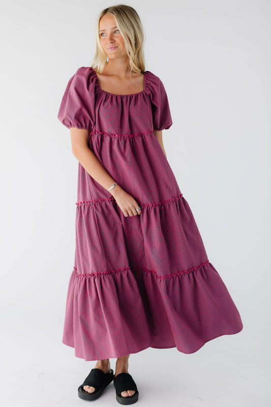 Woman wearing a loose fitting tiered midi dress in red & navy gingham with a square neckline and balloon sleeves.