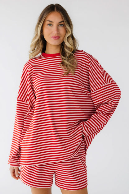 Woman wearing a loose fitting pink and red stripe shorts set with a crew neckline, drop shoulders and long sleeves with elastic waist shorts.