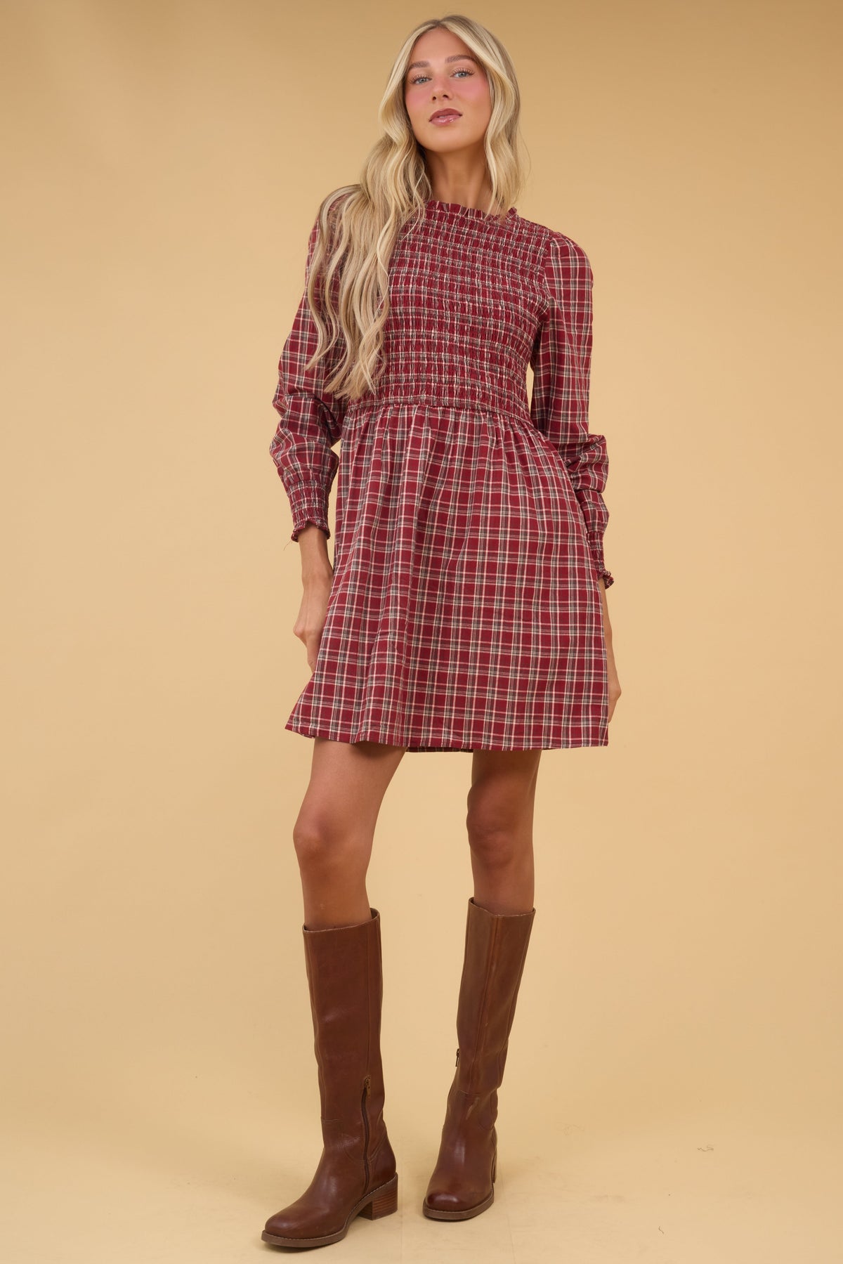 Young woman wearing a moest red plaid, short dress with long sleeves and smocked bodice.
