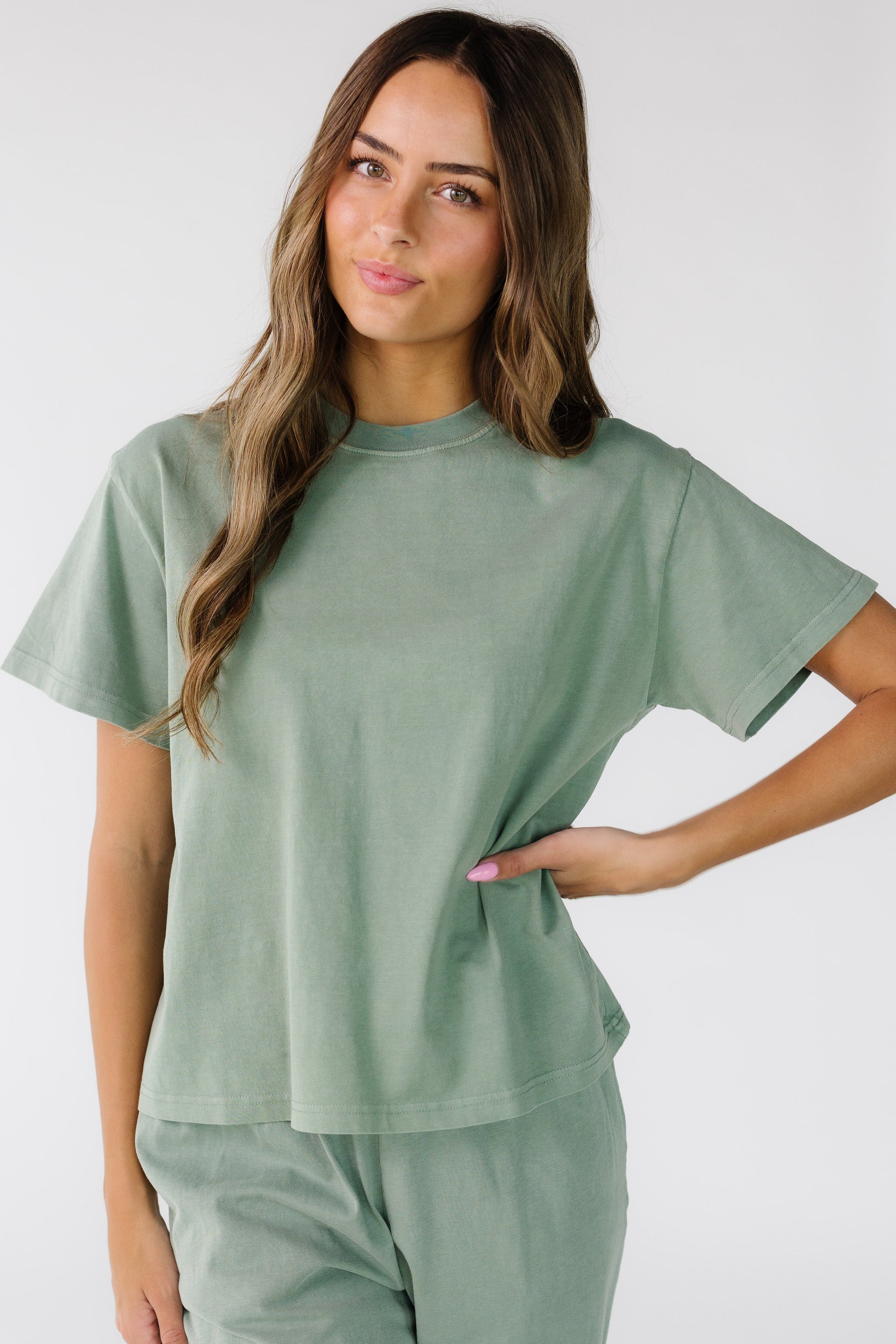 Woman wearing a modest sage green top with short sleeves and a crew neckline.