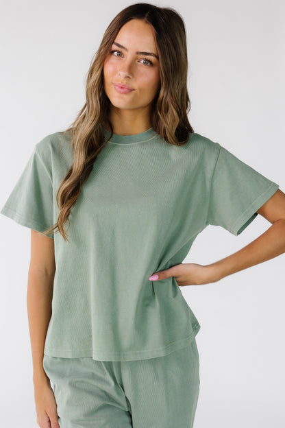 Woman wearing a modest sage green top with short sleeves and a crew neckline.