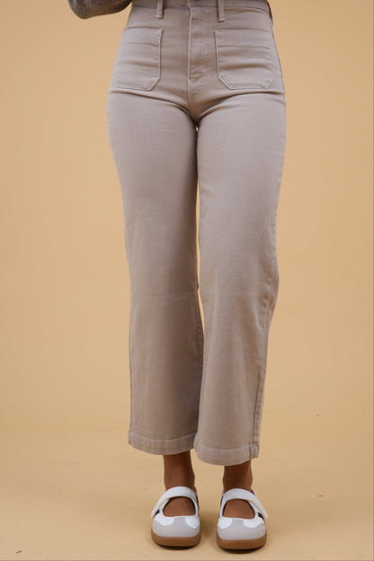 Young woman wearing a pair of light tan jeans with wider cut legs.