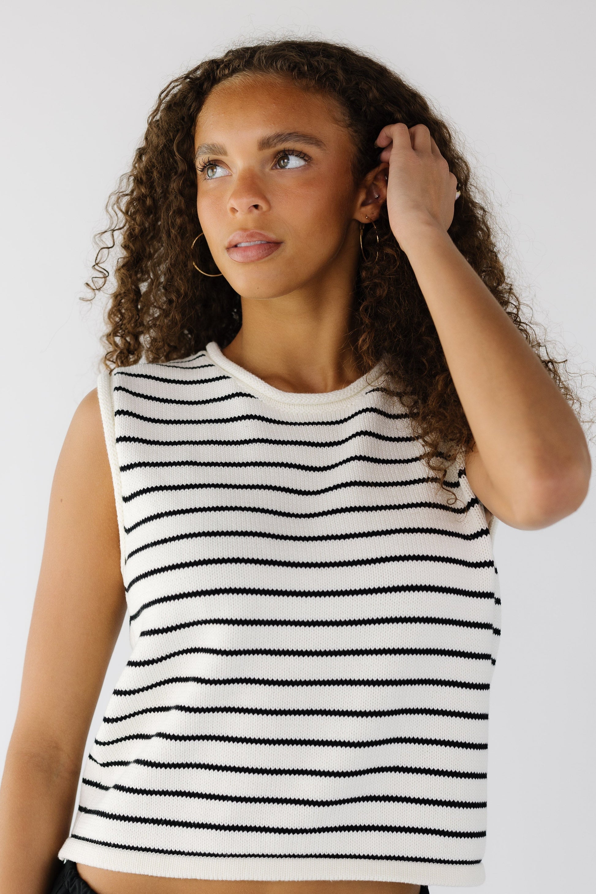 Teen girl wearing a white with black stripe sweater vest with rolled neckline and hems.