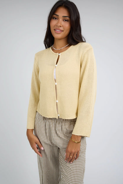 Woman wearing a loosely knit button down cardigan with a round neckline and long sleeves.