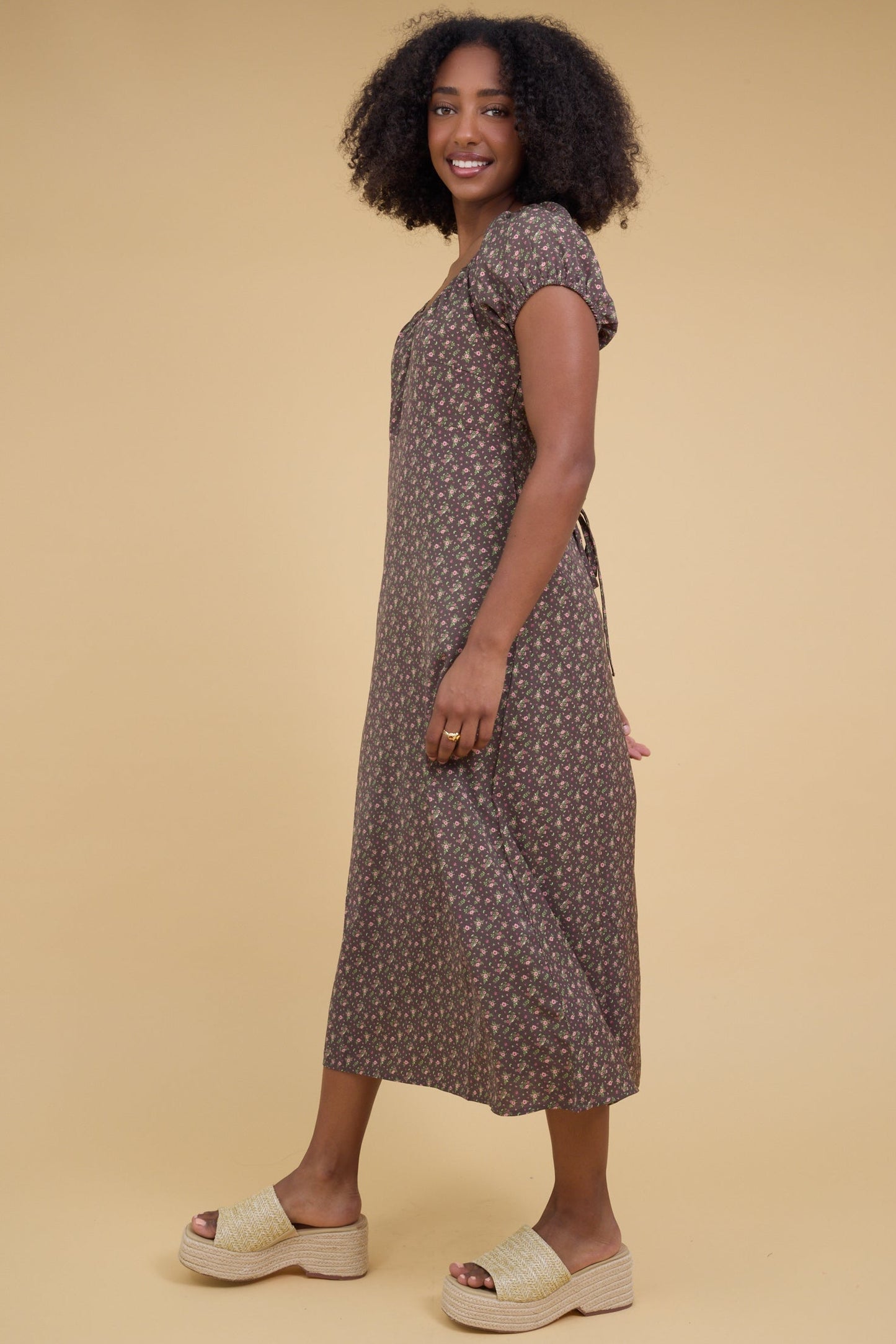 Side view of a woman wearing a slightly loose fitting midi dress with puff sleeves.