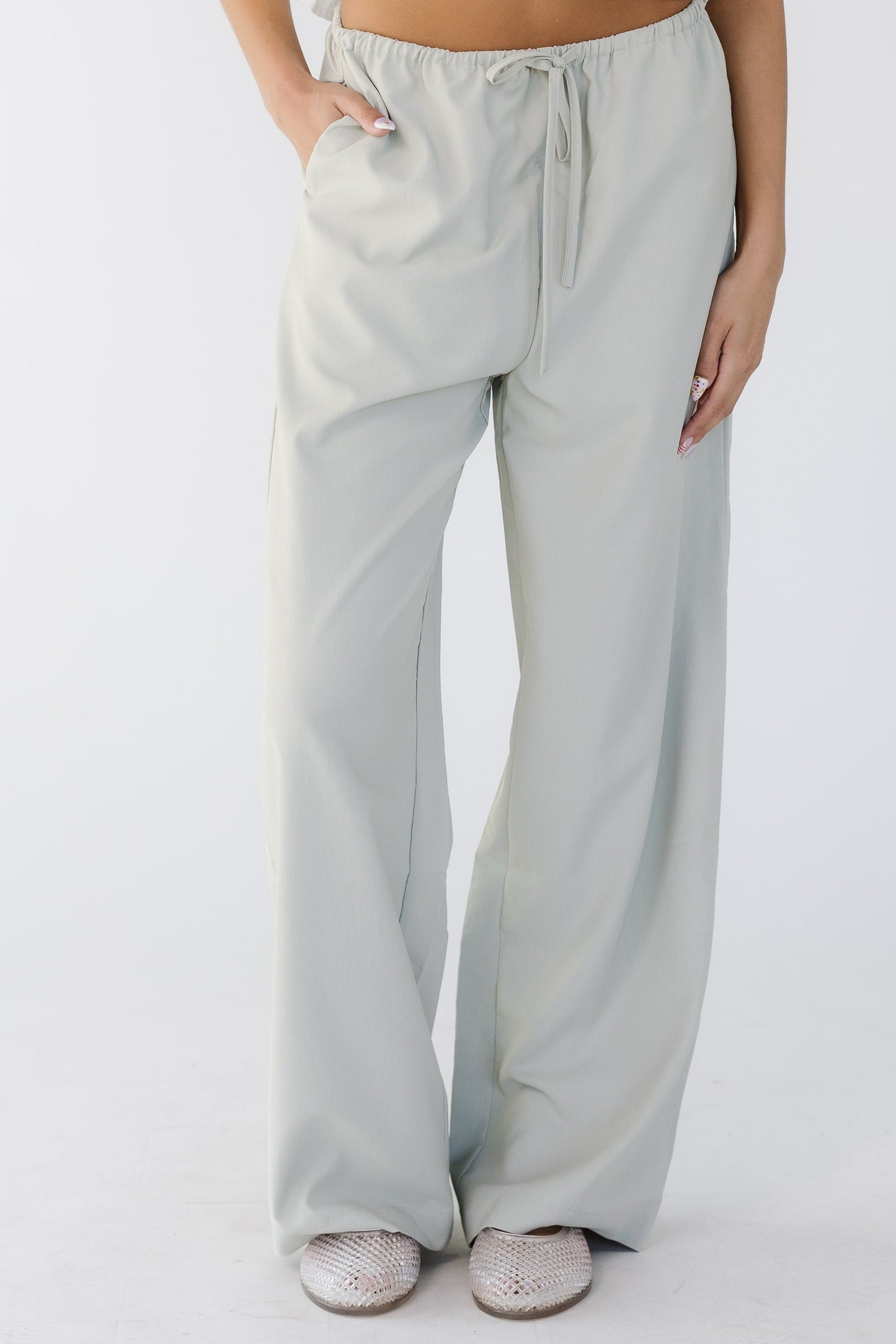 Teenage girl wearing modest taupe-grey wide leg pants with an elastic & drawstring waist and side pockets.
