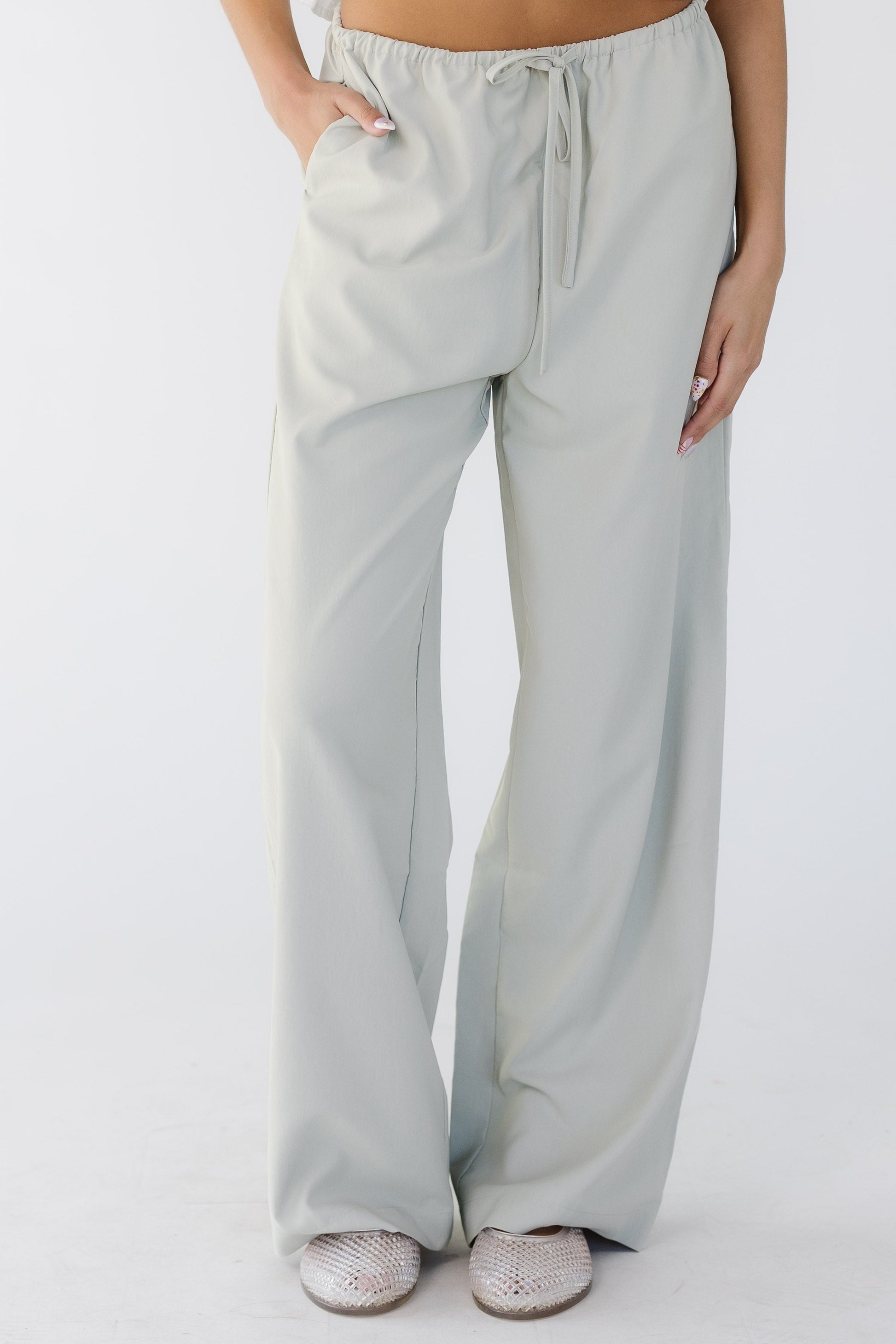 Teenage girl wearing modest taupe-grey wide leg pants with an elastic & drawstring waist and side pockets.