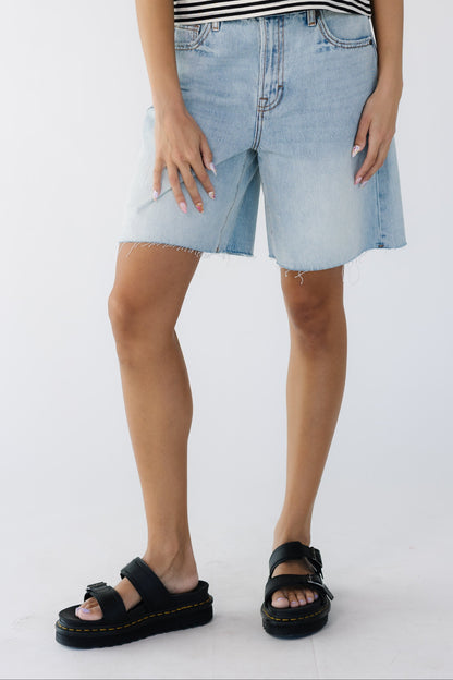 Teenage girl wearing a pair of loose fitting, wide leg denim shorts and scissor cut jeans.